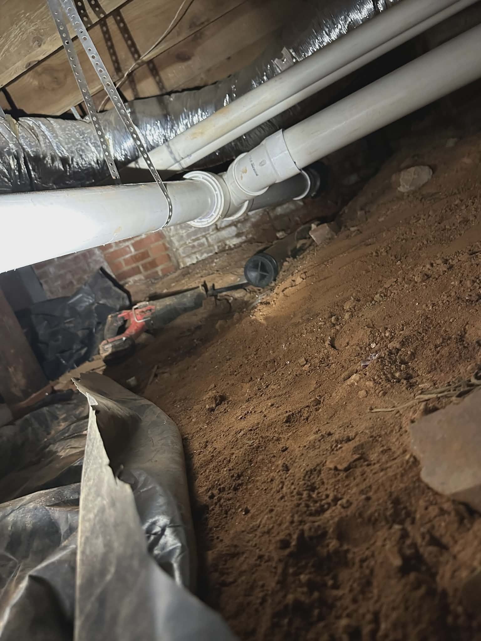 PVC pipe run through a residential crawlspace where a sump pump and discharge line are routed