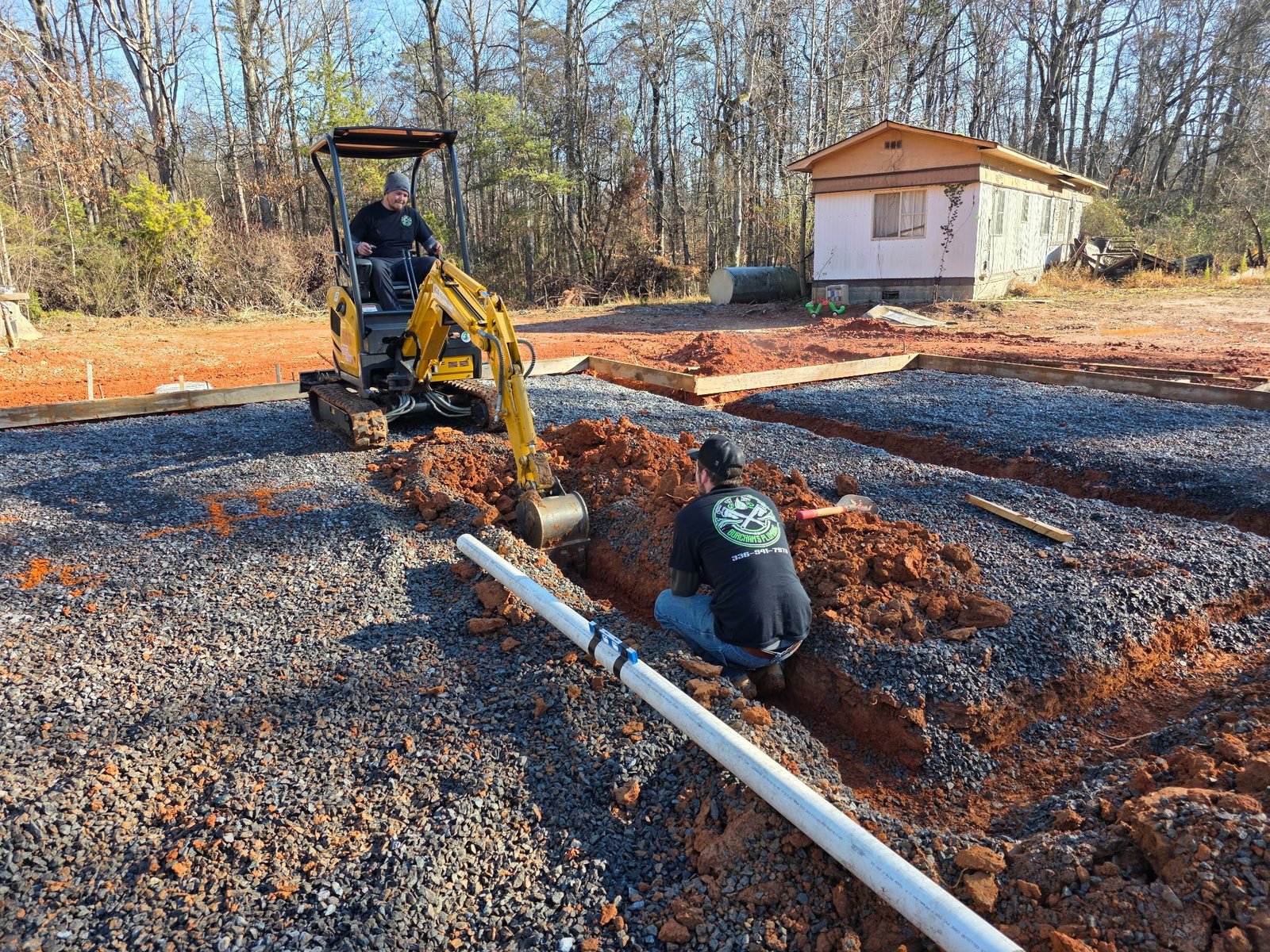Excavator digging a pipe trench for underground supply and sewer lines on a Yadkinville new build