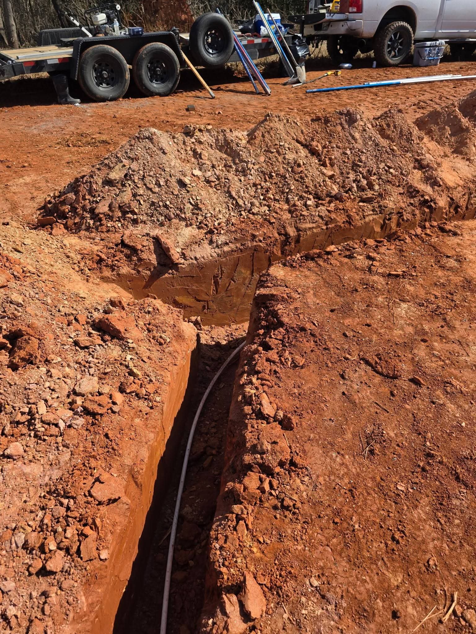 Underground pipeline preparation with graded trench and bedding for durable residential water or sewer installation before pipe placement.