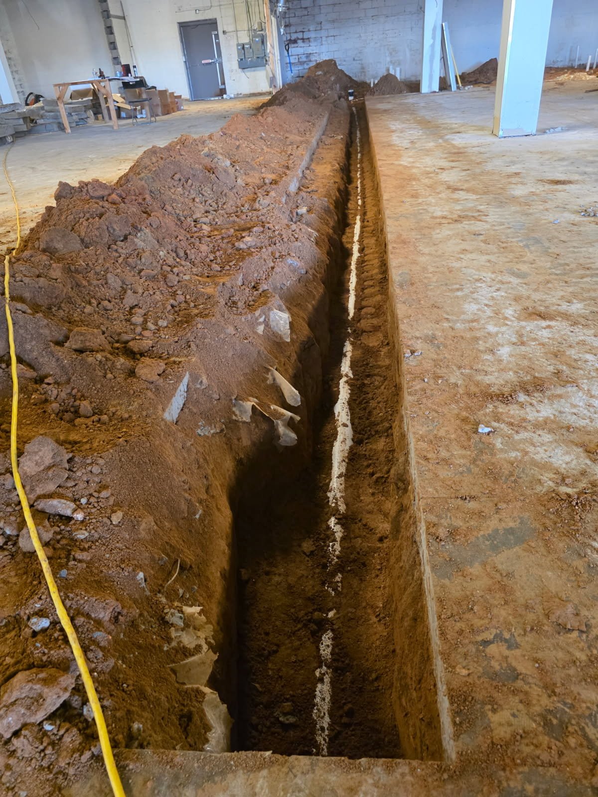 Interior underground pipeline installation during gym build-out with heavy-duty drain routing for locker rooms and floor drains.