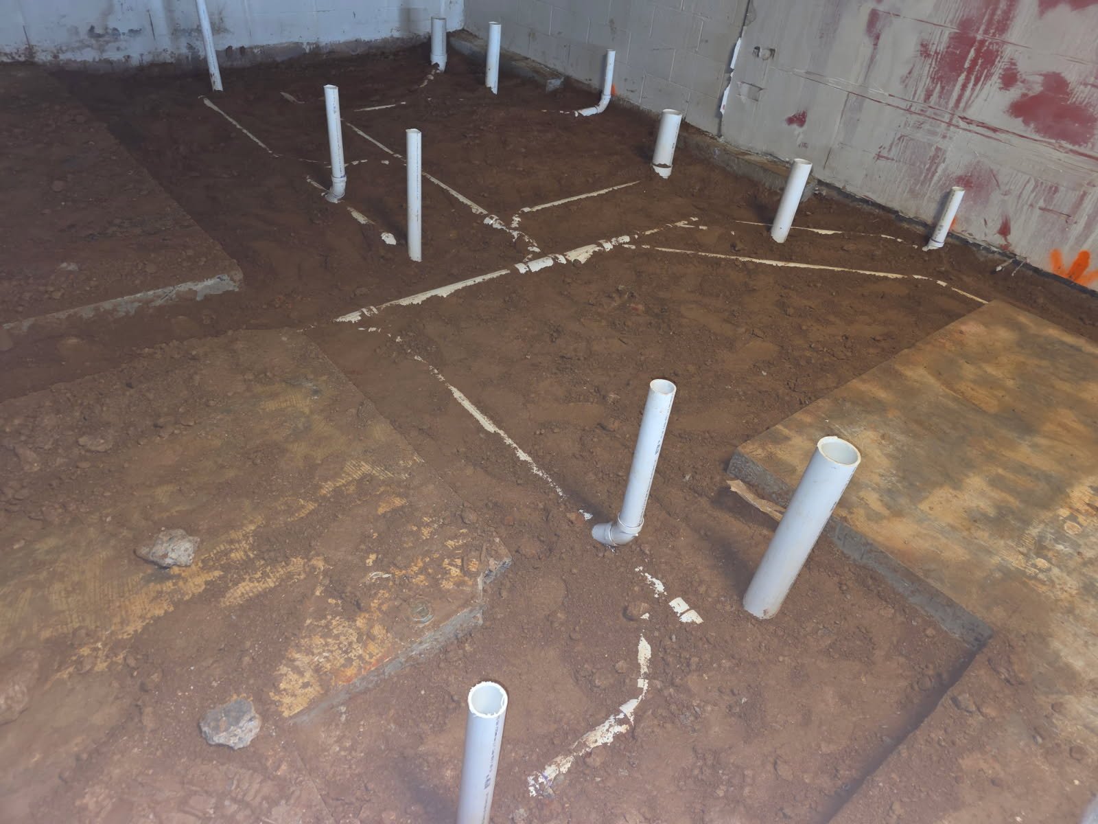 Commercial underground plumbing progress photo showing jointing and support for code-compliant drain systems.