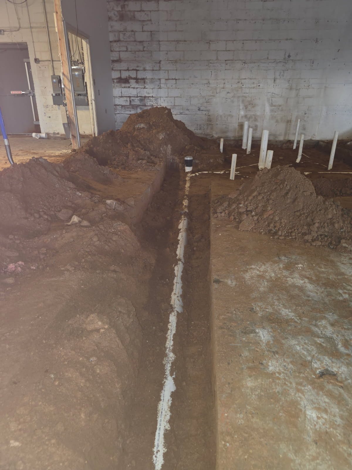 Gym underground plumbing installation with routing for fixtures and equipment drains in a high-traffic facility.