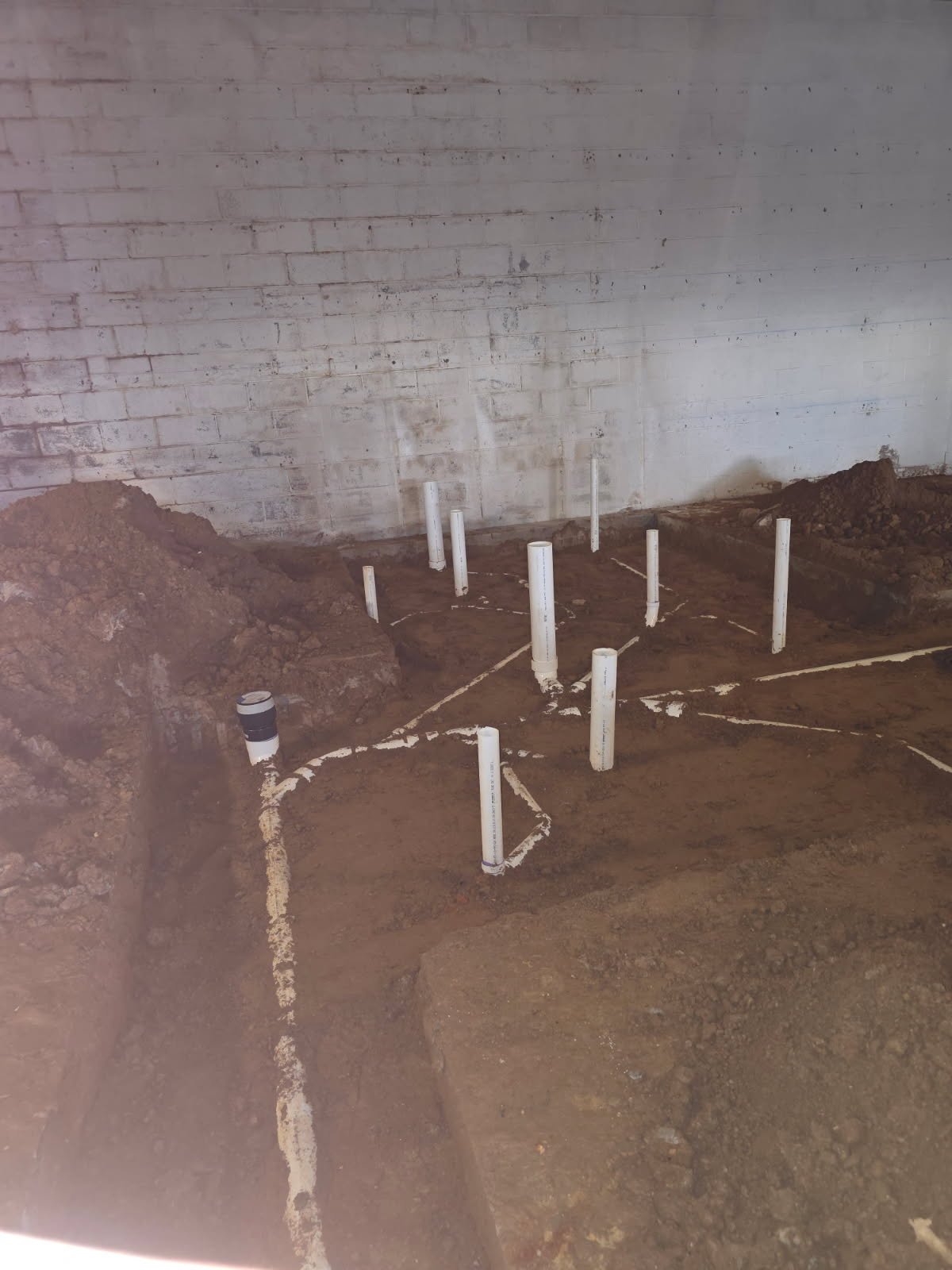Wide view of interior underground plumbing for a Yadkinville gym project with multiple branch lines.