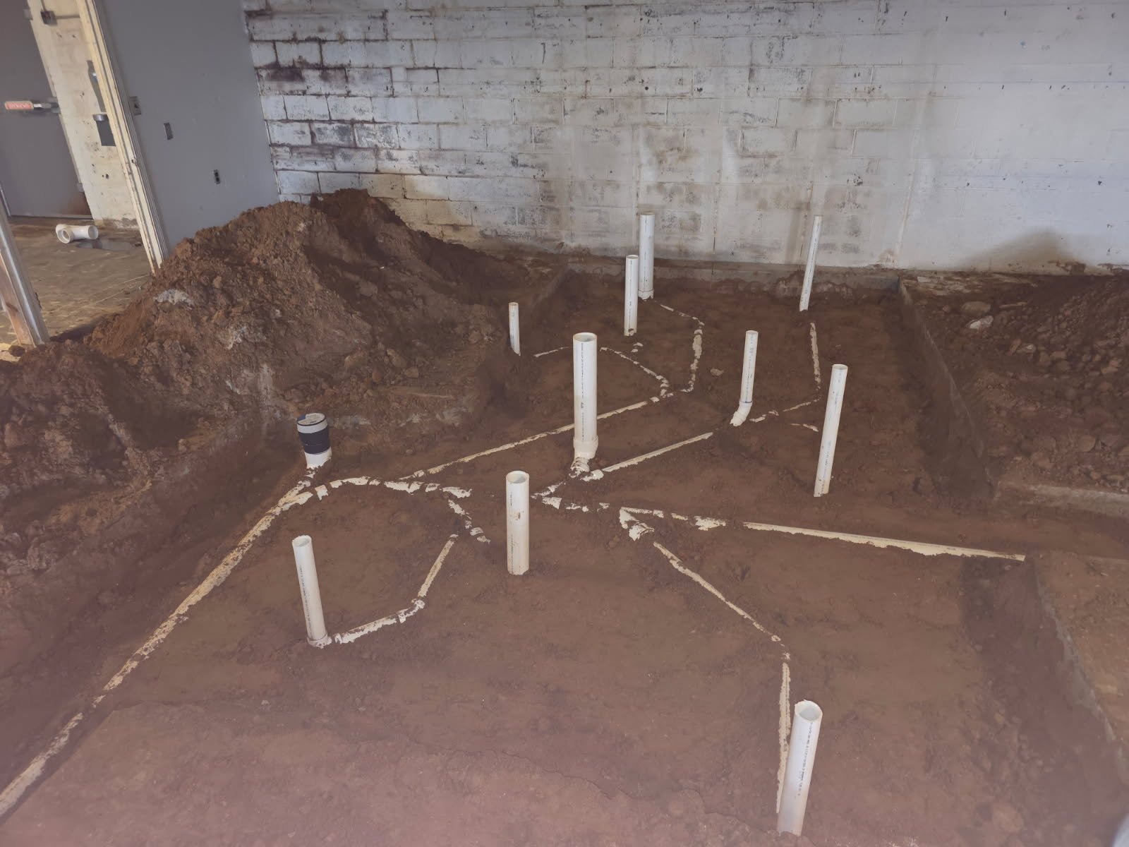 Underground plumbing layout for commercial restrooms and utility areas during active construction.